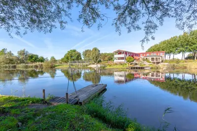 a house on a lake with a dock at Hajé Hotel Restaurant de Lepelaar in Lelystad