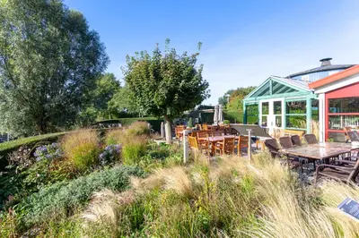 a garden with tables and chairs and a building at Hajé Hotel Restaurant de Lepelaar in Lelystad