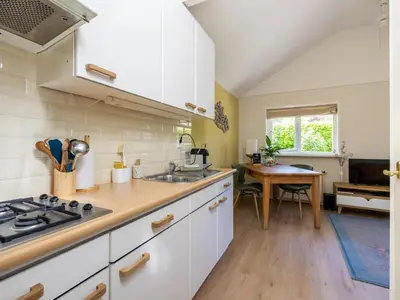 a kitchen with white cabinets and a sink and a table at De Groeter Lodge in Groet