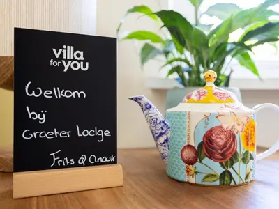 a sign on a table next to a tea kettle at De Groeter Lodge in Groet
