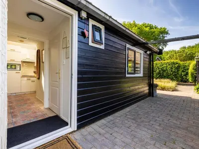 a black house with a door and a patio at De Groeter Lodge in Groet