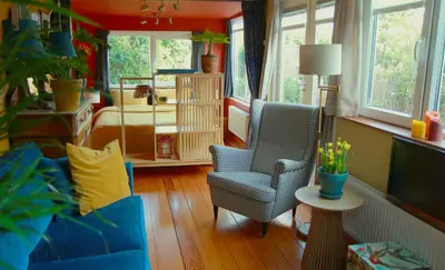 a living room with a blue chair and a bedroom at B&B Evergreen in Wijdewormer