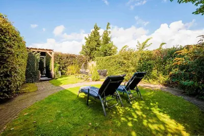 three chairs and a table in a yard at Wellness oase Egmond in Egmond aan den Hoef