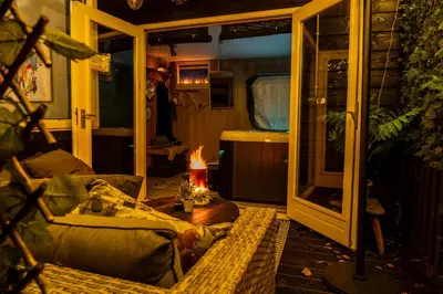 a living room with a couch and a table with a fire at Wellness oase Egmond in Egmond aan den Hoef