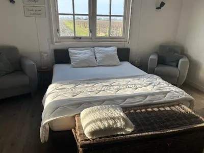 a bed in a room with two chairs and a window at Warmhuisje in Warmenhuizen