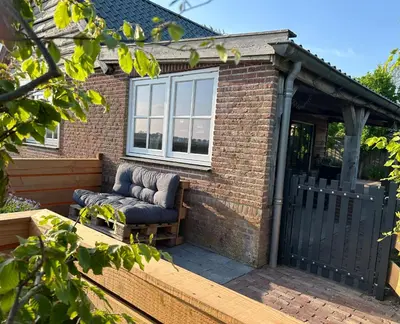 a couch sitting on a patio in front of a building at Warmhuisje in Warmenhuizen