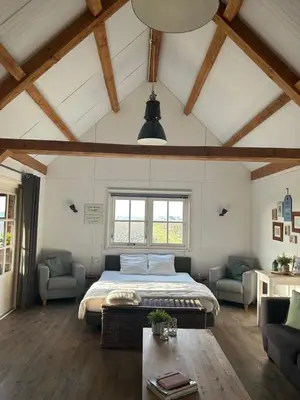 a bedroom with a bed and two chairs and a table at Warmhuisje in Warmenhuizen