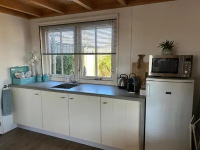 a kitchen with a sink and a microwave on a counter at Warmhuisje in Warmenhuizen