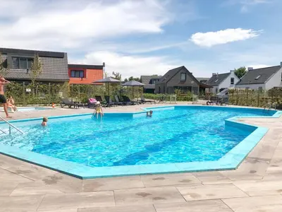 a swimming pool with people in the water at Chalet 588 op Recreatiepark De Wielen in Sint Maarten