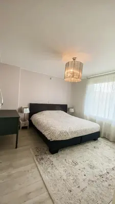 a bedroom with a bed and a table and a chandelier at Charming Entire Home Near Amsterdam in Hilversum