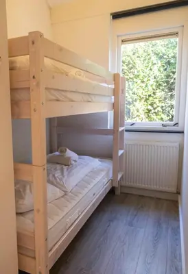 a bunk bed in a room with a window at Zeemeeuw in Egmond aan den Hoef
