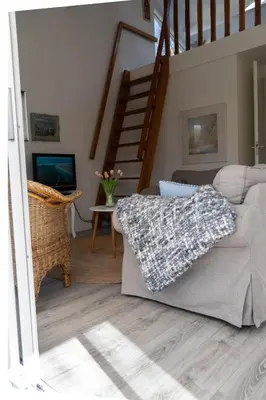 a living room with a couch and a staircase at Zeemeeuw in Egmond aan den Hoef