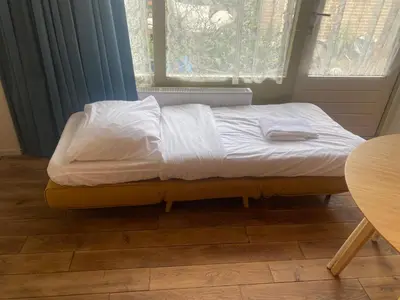 a bed with white sheets on it in a room at charming studio in Amsterdam-Noord in Amsterdam