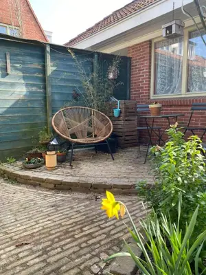 a patio with a bench and a table in front of a house at charming studio in Amsterdam-Noord in Amsterdam