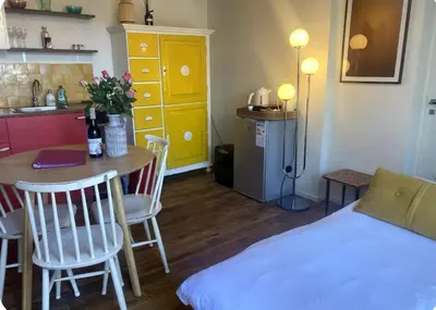 a room with a bed and a table and a kitchen at charming studio in Amsterdam-Noord in Amsterdam