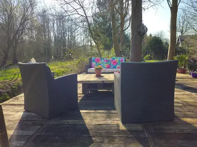 three wicker chairs and a coffee table on a patio at Heidy's Home, with Wellness Facilities in Zeewolde