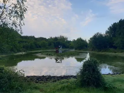 a small pond with a cross in the middle of it at Heidy's Home, with Wellness Facilities in Zeewolde