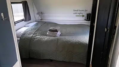 a bed in an rv with a blanket on it at De Rozenbottel met privé sanitair in Hensbroek