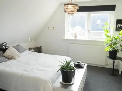 a bedroom with a white bed and potted plants at Karibu in Tuitjenhorn