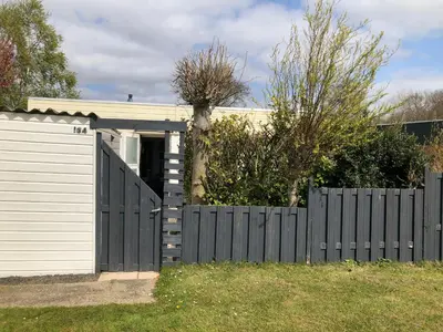 a house with a fence and a garage at 4 person Bungalow at beach, sea, dunes, lake, forestside in Noordwijkerhout