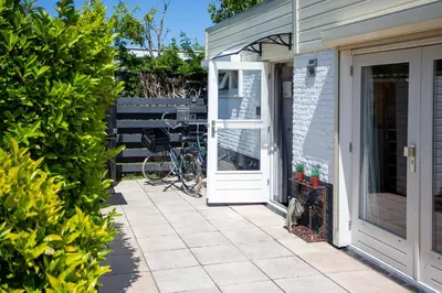 a white door on a house with a patio at 4 person Bungalow at beach, sea, dunes, lake, forestside in Noordwijkerhout