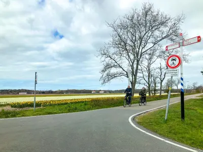 two people riding bikes on a road with flowers at 4 person Bungalow at beach, sea, dunes, lake, forestside in Noordwijkerhout
