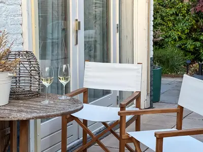 a table and chairs on a porch with wine glasses at 4 person Bungalow at beach, sea, dunes, lake, forestside in Noordwijkerhout