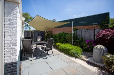 a patio with a table and chairs and a tent at 4 person Bungalow at beach, sea, dunes, lake, forestside in Noordwijkerhout