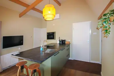 a kitchen with a counter with a sink and two stools at Het Vogelhuisje in Egmond aan den Hoef