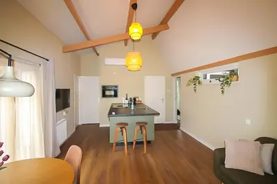 a kitchen and living room with a table and stools at Het Vogelhuisje in Egmond aan den Hoef