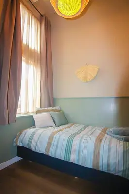 a small bedroom with a bed and a window at Het Vogelhuisje in Egmond aan den Hoef