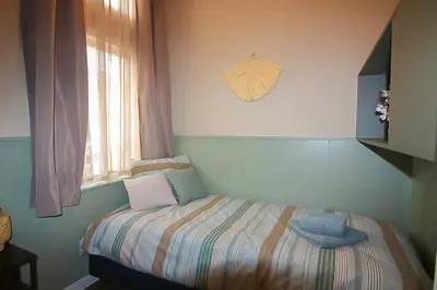 a small bed in a room with a window at Het Vogelhuisje in Egmond aan den Hoef