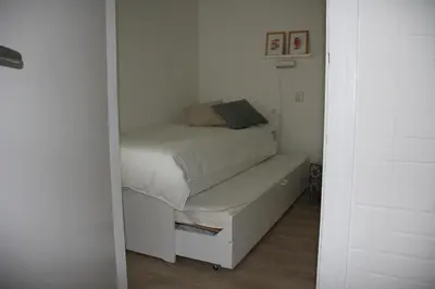 a small bedroom with a bed and a bench at Strandlicht in Egmond aan Zee