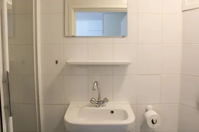 a white bathroom with a sink and a mirror at Strandlicht in Egmond aan Zee