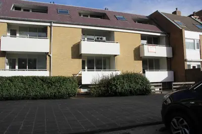 an apartment building with white balconies in a parking lot at Strandlicht in Egmond aan Zee