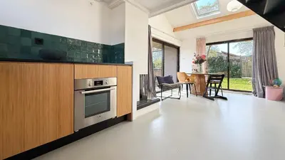 a kitchen with a stove and a table with chairs at Het Duinhuisje by Droomvilla in Egmond aan den Hoef