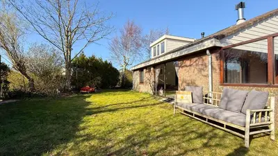 a couch sitting on a lawn next to a house at Het Duinhuisje by Droomvilla in Egmond aan den Hoef