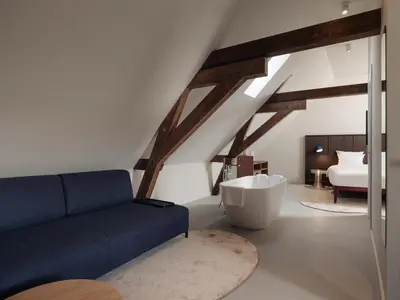 a living room with a blue couch and a bath tub at Conscious Hotel Oudegracht in Utrecht