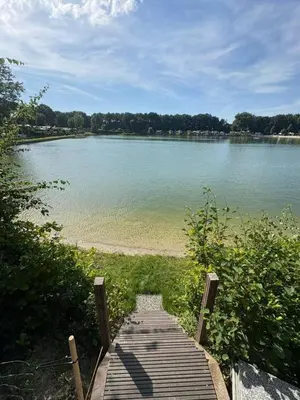 a wooden boardwalk leading to a large body of water at Luxe nieuwbouw chalet aan het water in Hoevelaken