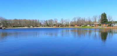 a large blue lake with houses in the background at Luxe nieuwbouw chalet aan het water in Hoevelaken