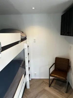 a room with a bunk bed and a chair at Luxe nieuwbouw chalet aan het water in Hoevelaken