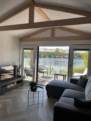 a living room with a couch and a view of the water at Luxe nieuwbouw chalet aan het water in Hoevelaken