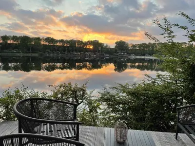 a view of a lake with two chairs on a deck at Luxe nieuwbouw chalet aan het water in Hoevelaken