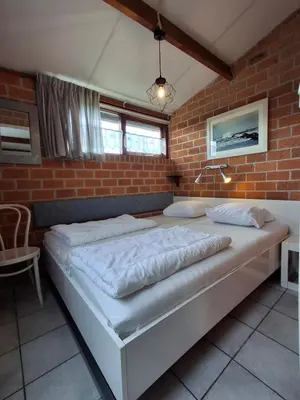 a large bed in a room with a brick wall at Rekerlanden 210 in Schoorldam