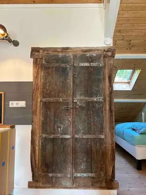 an old wooden door in a room with a bed at Sfeervol Overnachten in de Kerk in Amersfoort
