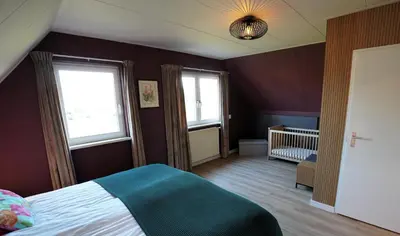 a bedroom with a bed and two windows and a crib at De Sas in Lisse in Lisse