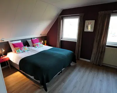 a bedroom with a bed and two windows at De Sas in Lisse in Lisse