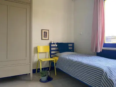 a small bedroom with a bed and a yellow chair at Holiday Home in Noordwijkerhout near Lake in Noordwijkerhout