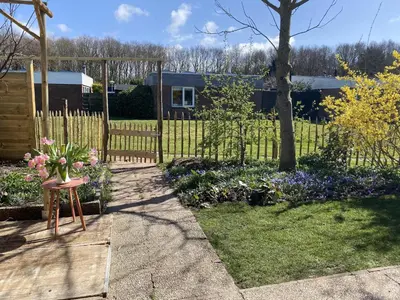 a garden with a vase of flowers on a stool at Holiday Home in Noordwijkerhout near Lake in Noordwijkerhout