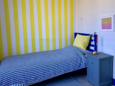 a bedroom with a blue and yellow striped wall at Holiday Home in Noordwijkerhout near Lake in Noordwijkerhout